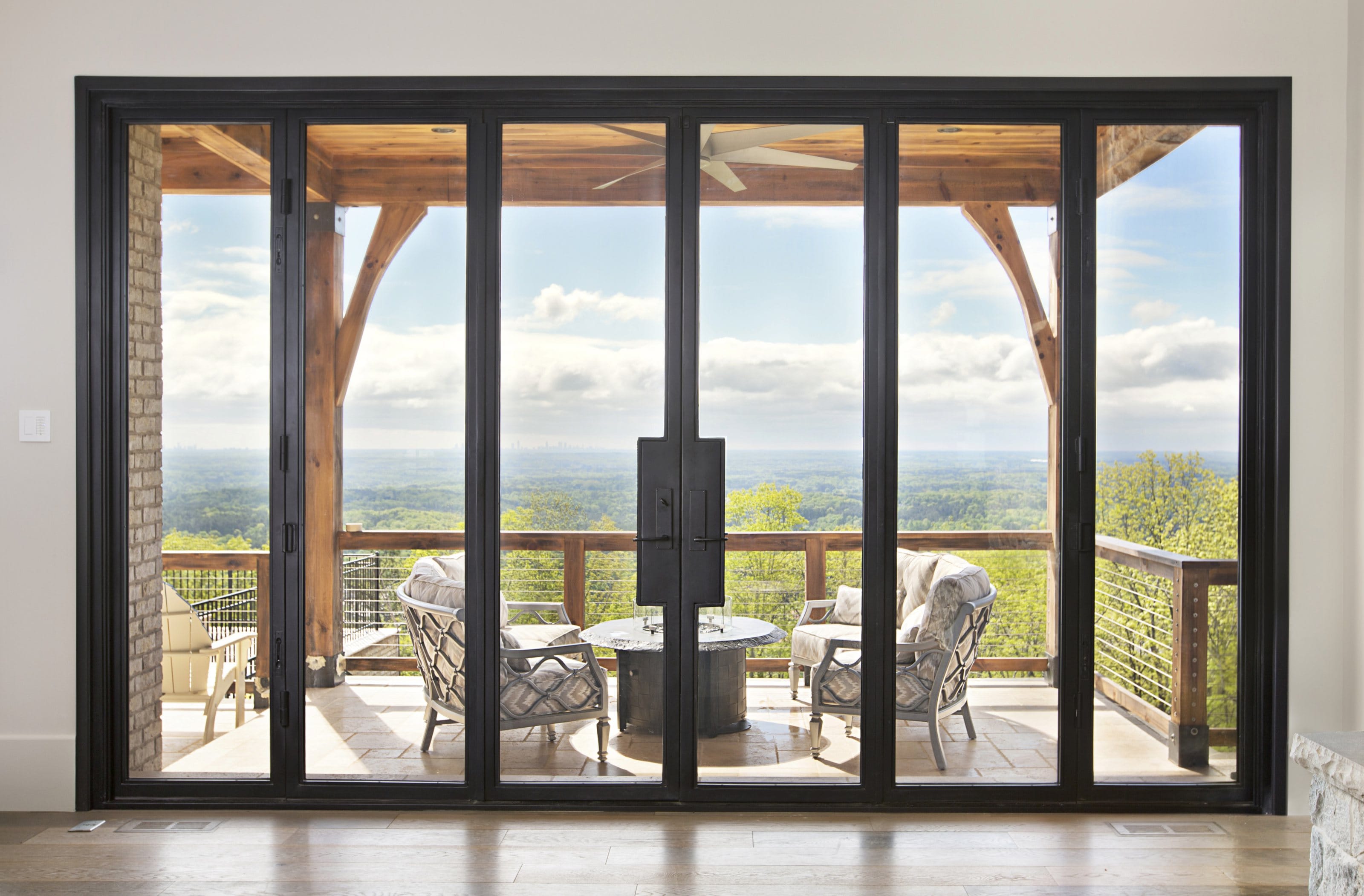 Multi-panel aluminum sliding door opening from an interior onto a covered terrace with a long view.