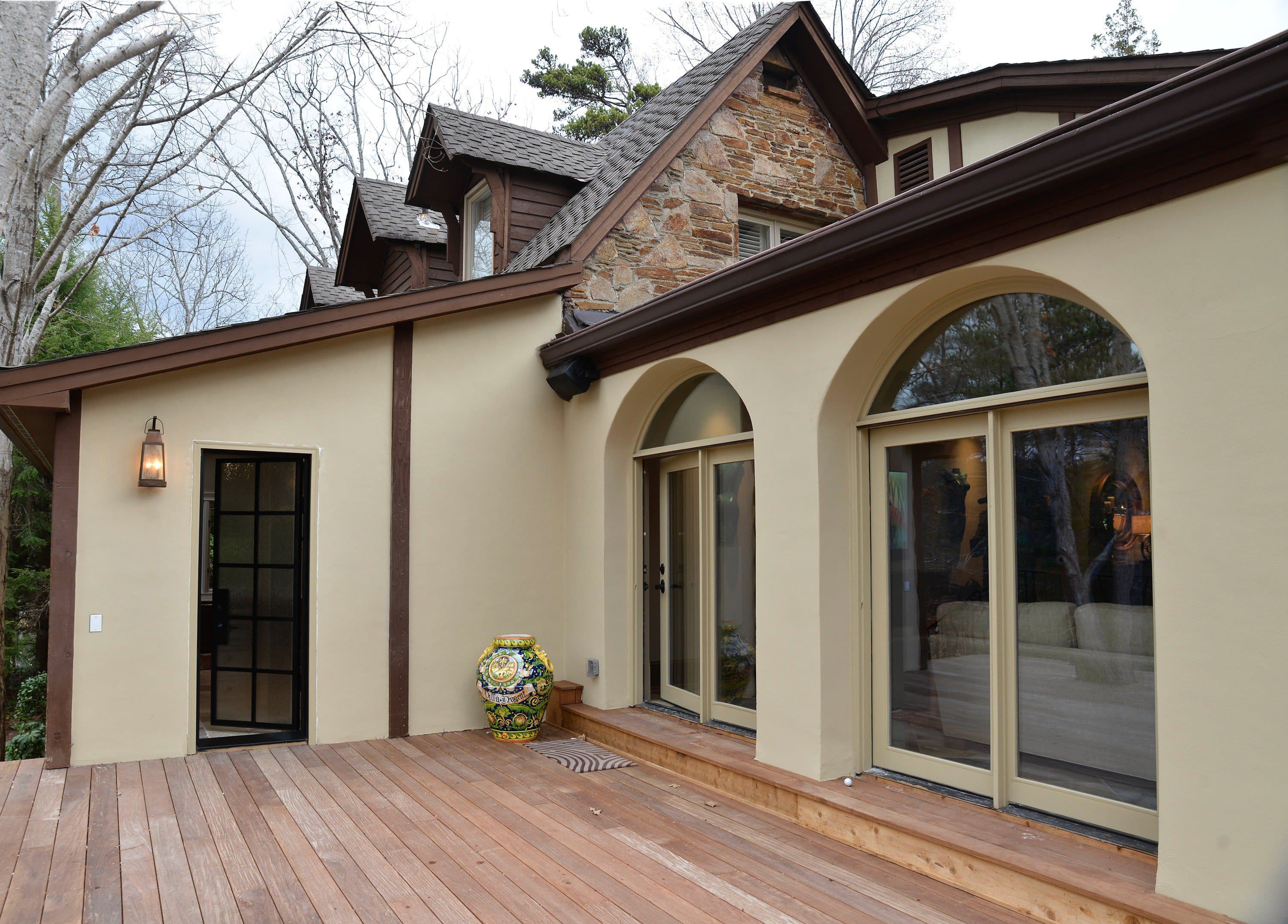 A stucco elevation with arched glazed openings onto a timber deck.