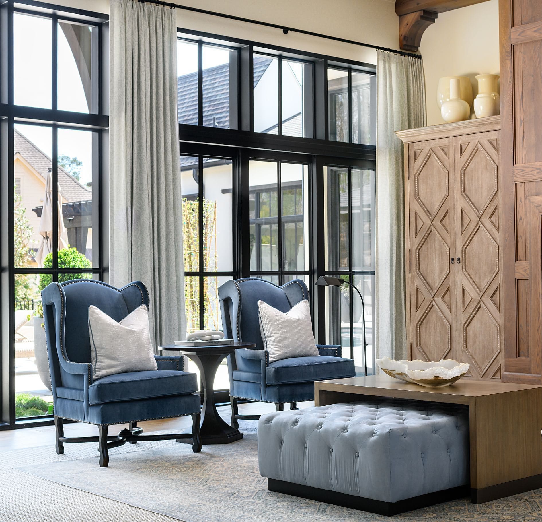 A sitting room with tall dark-framed windows and warm timber joinery.